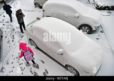 I pedoni a piedi passato auto coperti di neve durante una nevicata nella città di Yantai, est della Cina di provincia di Shandong, 7 dicembre 2018. Un ondata di freddo br Foto Stock