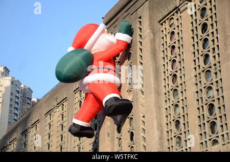 Un palloncino di giocattoli di Babbo Natale che porta un gigante borsa regalo è scalare la parete del 1933 Old Millfun in Cina a Shanghai, 18 dicembre 2018. Foto Stock