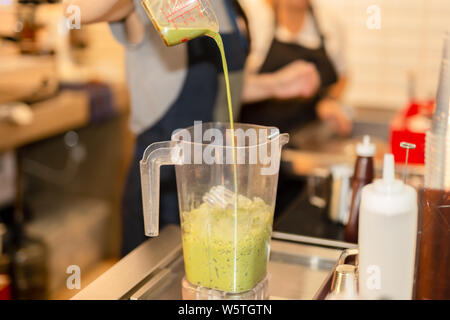 Barista versando matcha geen tea in Blender fare frullati in cafe. Foto Stock