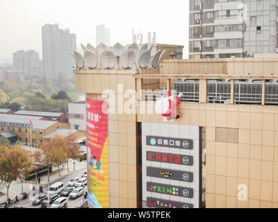 Un palloncino di giocattoli di Babbo Natale che porta un gigante borsa regalo è scalare la parete di un department store nella città di Nantong, est cinese della provincia di Jiangsu, 1 Decem Foto Stock