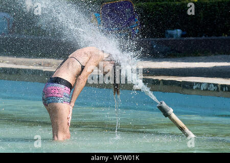 25/07/2019. Battersea, Londra, Regno Unito. Una donna non si raffredda in acqua fontane in Battersea Park come un ondata di caldo spazza il Regno Unito. Foto Stock