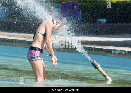 25/07/2019. Battersea, Londra, Regno Unito. Una donna non si raffredda in acqua fontane in Battersea Park come un ondata di caldo spazza il Regno Unito. Foto Stock