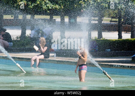 25/07/2019. Battersea, Londra, Regno Unito. Una donna non si raffredda in acqua fontane in Battersea Park come un ondata di caldo spazza il Regno Unito. Foto Stock