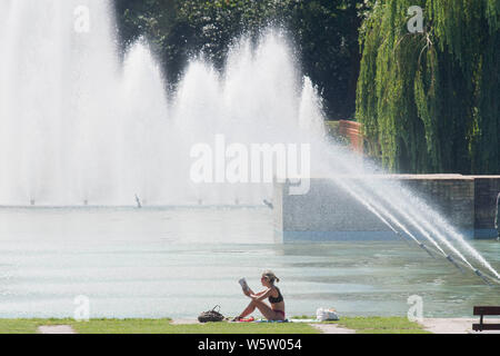 25/07/2019. Battersea, Londra, Regno Unito. Una donna che legge le fontane, nella calura del mezzogiorno in Battersea Park come un ondata di caldo spazza il Regno Unito. Foto Stock