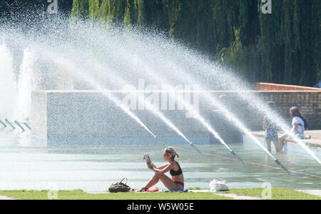 25/07/2019. Battersea, Londra, Regno Unito. Una donna che legge le fontane, nella calura del mezzogiorno in Battersea Park come un ondata di caldo spazza il Regno Unito. Foto Stock