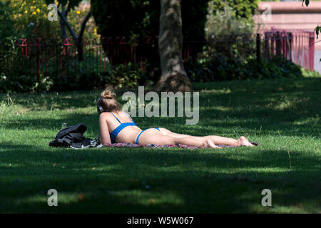 25/07/2019. Battersea, Londra, Regno Unito. Una donna sunbathes sul prato di Battersea Park come un ondata di caldo spazza il Regno Unito. Foto Stock