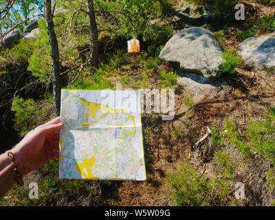 Controllare la mappa all'interno di orienteering esegui. Sportivo in esecuzione nel difficile terreno roccioso. Foto Stock