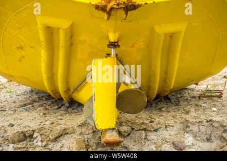 La parte posteriore di una barca da pesca che si trova sulla spiaggia. Il timone e l'elica sono chiaramente visibili. Chlopy, Polonia 2019. Foto Stock