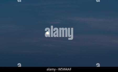 La luna nel cielo di sera durante l'ora di blu. Foto Stock