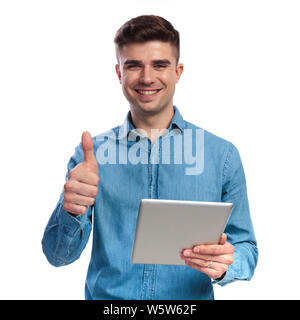 Giovane uomo sorridente facendo segno ok mantenendo compressa su sfondo bianco Foto Stock