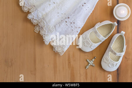 Battesimo babbucce, crhistening Vintage dress, candel e ciondolo di cristallo su rustico sfondo di legno - vista superiore foto con lo spazio di testo Foto Stock