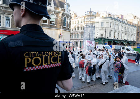 Un poliziotto sta di guardia come rivendicare il potere manifestanti raccogliere fuori dalla stazione di Liverpool Street prima di passare a 41 Moorgate durante una dimostrazione sui combustibili fossili e centrali a gas.i manifestanti stessi incollato a ciò che essi hanno pensato che era il capo ufficio di Drax Power, tuttavia, Drax aveva da tempo spostata fuori. Sono riusciti a chiusura di diverse strade e attirare la presenza della polizia anche se. Foto Stock