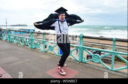 Brighton, Regno Unito. Il 30 luglio, 2019. Emily Green pende su per il suo abito dopo la laurea dall'Università di Brighton come essa celebra su un molto ventoso Mare successivamente . Credito: Simon Dack/Alamy Live News Foto Stock