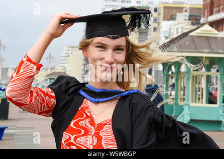 Brighton, Regno Unito. Il 30 luglio, 2019. Lois Green pende sul suo mortaio bordo dopo la laurea dall'Università di Brighton su un ventoso Mare dopo la cerimonia . Credito: Simon Dack/Alamy Live News Foto Stock