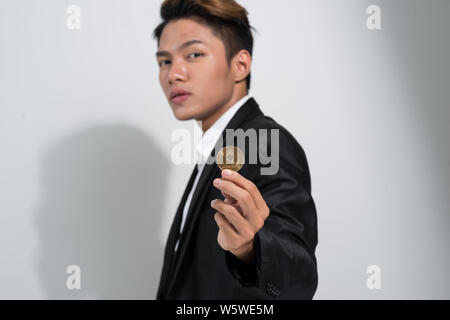 Uomo asiatico in abito nero azienda Bitcoin su sfondo bianco Foto Stock