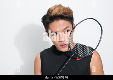 Close up asiatici lettore di badminton racchetta tenuta su sfondo bianco. Foto Stock