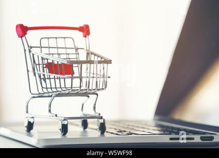 Shopping su Internet. Computer portatile, piccolo carrello e carte di  credito sul tavolo al coperto, guardaroba Foto stock - Alamy