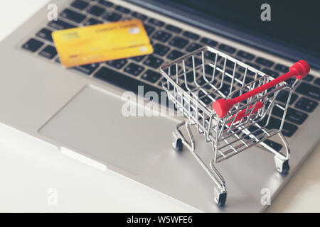 Shopping online concetto, carrello e una carta di credito con il laptop sulla scrivania Foto Stock