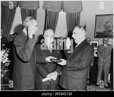 Fotografia di W. Averell Harriman tenendo il giuramento di ufficio come direttore della sicurezza reciproca agenzia nell'ufficio ovale, come Chief Justice Fred Vinson amministra il giuramento e il Presidente Truman guarda a. Foto Stock