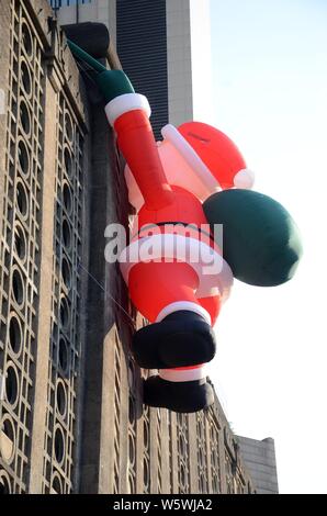 Un palloncino di giocattoli di Babbo Natale che porta un gigante borsa regalo è scalare la parete del 1933 Old Millfun in Cina a Shanghai, 18 dicembre 2018. Foto Stock