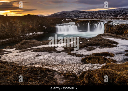 Il ghiacciaio del fuso di acqua che scorre in congelati cascate Godafoss presso sunrise, Islanda Foto Stock