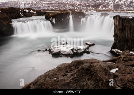 Il ghiacciaio del fuso di acqua che scorre in congelati cascate Godafoss presso sunrise, Islanda Foto Stock