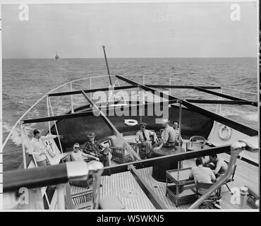 Fotografia di membri del Presidente Truman del partito la rilassante dopo Ponte del suo yacht, il Museo della Portaerei U.S.S. WILLIAMSBURG, come il Museo della Portaerei U.S.S. WILLIAM C. LAWE fornisce escort in background durante una vacanza crociera a Key West, Florida. Foto Stock