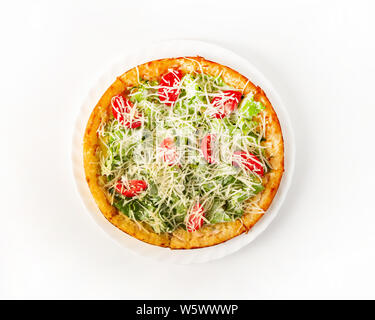 Caesar pizza con pollo su una piastra, vista dall'alto. Formaggio Mazarela strofinato sulla parte superiore. Il cibo italiano. Foglie di insalata e pomodori a fette. Su uno sfondo bianco, Foto Stock