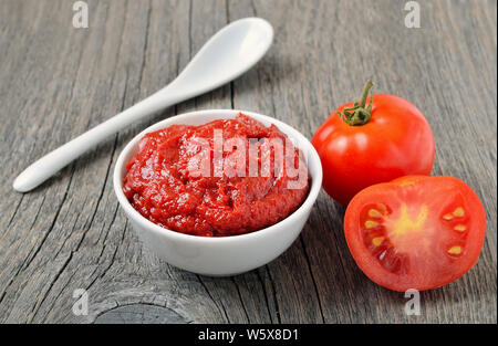 Salsa di pomodoro in una ciotola bianco e pomodori freschi su sfondo di legno Foto Stock