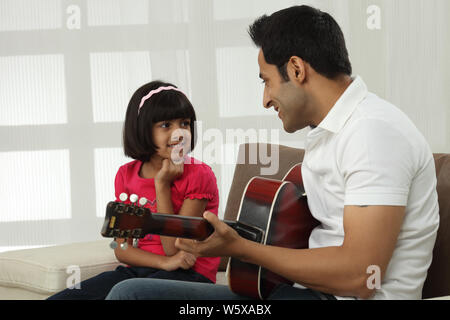 Uomo che suona la chitarra per sua figlia Foto Stock