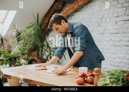 Bel giovane preparazione impasto per il pane fatto in casa in cucina Foto Stock