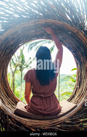 Un turista femminile è seduta su un grande nido di uccelli su un albero a isola di Bali, Indonesia Foto Stock