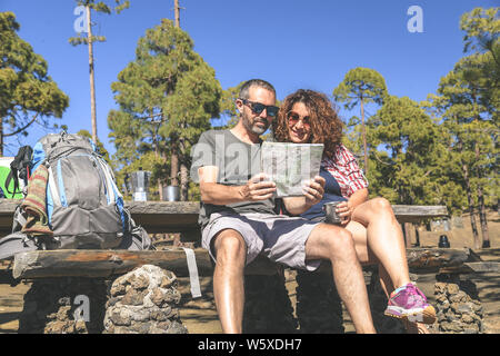 Paio di prendere un periodo di riposo dopo il trekking l uomo e la donna che guarda la mappa per trovare il percorso di trekking Caucasian persone bere un caffè in una giornata di sole a Foto Stock