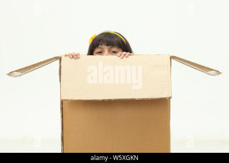 Girl peeking out of a cardboard box Stock Photo