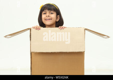 Girl peeking out of a cardboard box Stock Photo