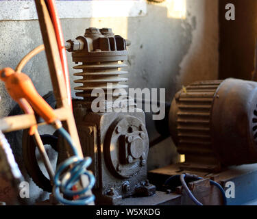 Compressore aria in un garage avente la testa del compressore nella messa a fuoco Foto Stock