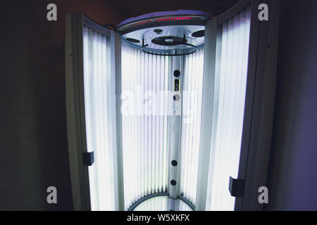 Abbronzante verticale solarium turbo macchina leggera con blu brillante di luce di lampade a raggi ultravioletti per la concia e la cura della pelle. Svuotare l'abbronzatura solarium moderno Foto Stock