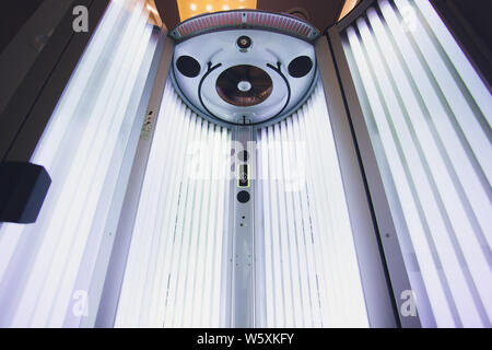 Abbronzante verticale solarium turbo macchina leggera con blu brillante di luce di lampade a raggi ultravioletti per la concia e la cura della pelle. Svuotare l'abbronzatura solarium moderno Foto Stock