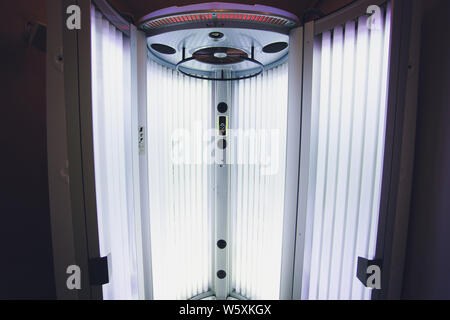 Abbronzante verticale solarium turbo macchina leggera con blu brillante di luce di lampade a raggi ultravioletti per la concia e la cura della pelle. Svuotare l'abbronzatura solarium moderno Foto Stock