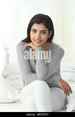 Portrait of a woman sitting on the bed smiling Stock Photo