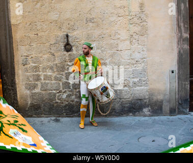 Un giovane uomo in abito medievale e del costume suona la batteria durante la sfilata del Palio di Siena, Italia Foto Stock