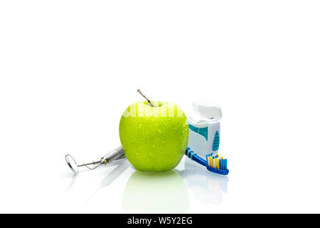 Gli strumenti del dentista con mela verde di spazzolino e filo interdentale isolare su sfondo bianco.- Immagine Foto Stock