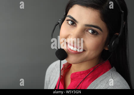 Imprenditrice che indossa gli auricolari e sorridente Foto Stock