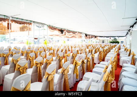 Temporanea di condizionatore aria tenda interna per eventi esterni nel giorno. All'interno tende ha moquette rossa e un sacco di sedia coperta da un panno bianco e golde ri Foto Stock