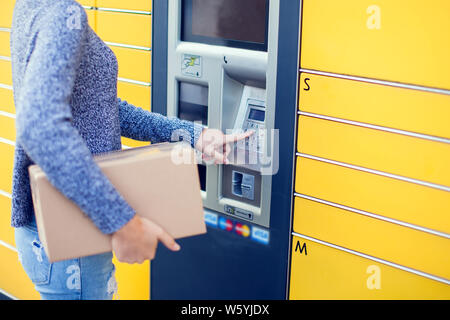 Donna client utilizzando automated self service post macchina terminale o armadietti per il deposito del pacco per lo storage Foto Stock