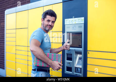 L'uomo client utilizzando automated self service post macchina terminale o armadietti per il deposito del pacco per lo storage Foto Stock