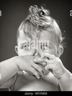 Anni Cinquanta WIDE-EYED ALLARMATO BABY guardando fuori a lato LE MANI CHE COPRE LA PARTE INFERIORE DEL VISO - b9551 HAR001 INFERIORE HARS PAURA SPAVENTATI ESPRESSIONI DI COPERTURA TURBATO B&W TRISTEZZA BUG-EYED testa e spalle emozione potente sentimento di parte dell'UMORE GLUM concettuale close-up paurosi emozione emozioni emotivo spavento novellame miserabile STARTLED ALLARMATO BAMBINA IN BIANCO E NERO di etnia caucasica HAR001 VECCHIO incerta Foto Stock