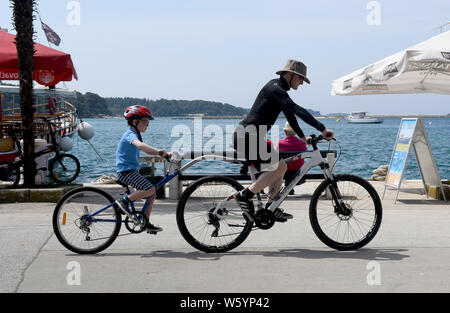 Padre e figlio a cavallo di un tag-un-lungo o bici a rimorchio e barra di traino Foto Stock