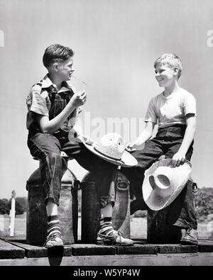 1940s Farm due ragazzi seduti sul latte zangole parlando sorridente indossando il denim holding di cappelli di paglia BRUNETTE BOY indossando tute da BIB - d1178 HAR001 HARS CASEIFICIO spazio copia amicizia a mezza lunghezza tute le lattine agricola fratelli maschi DENIM AGRICOLTURA B&W ESTATE BRUNETTE felicità allegro scelta gli agricoltori a basso angolo di pari livello di distribuzione sorrisi DAIRYING COLLEGAMENTO FRIENDLY GIOIOSA DAIRY FARM BIB bidoni per la crescita della cooperazione novellame pre-teen pre-teen BOY STAGIONE convivere in bianco e nero di etnia caucasica HAR001 in vecchio stile Foto Stock