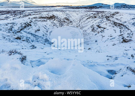 Vista panoramica del Vulcano Kerid con neve e ghiaccio nel cratere vulcanico lago in inverno sotto un cielo blu chiaro. Situato nella zona Grímsnes in così Foto Stock